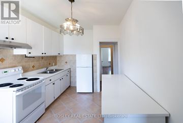 Toronto (Trinity-Bellwoods) apartment for rent - A white kitchen with a Bosley Real Estate LTD sign.