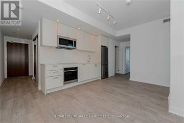 Toronto (High Park-Swansea) condo for rent - A spacious kitchen with white cabinets and a wooden floor.