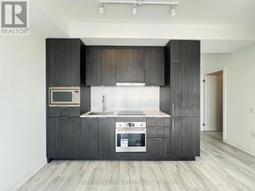 Toronto (Newtonbrook East) condo for rent - A modern kitchen with dark wood cabinets and a white backsplash.
