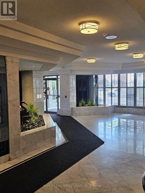 Toronto (Kennedy Park) condo for rent - A hallway with a black carpet and a stone pillar.