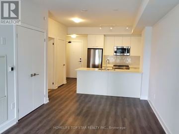 Mississauga (City Centre) condo for rent - A kitchen area with white cabinets and a wooden floor.