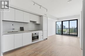 Toronto (Thorncliffe Park) condo for rent - A modern kitchen with white cabinets and a view of the city.
