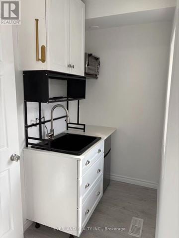 Toronto (Annex) fourplex for rent - A small white kitchen with a black counter top.