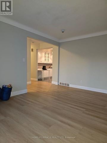 St. Catharines (Oakdale) apartment for rent - A room with wooden flooring and a kitchen visible through the doorway.