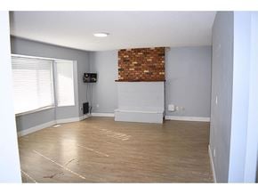 Surrey apartment for rent - A room with a wooden floor and a brick wall.