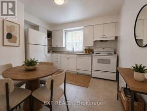 Toronto (Mimico) multi-family for rent - A kitchen with white appliances and a round table with chairs.