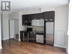 Toronto (Waterfront Communities) condo for rent - A kitchen with black cabinets and stainless steel appliances.