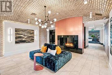 Hamilton (Stoney Creek) condo for rent - A living room with a blue velvet couch and a fireplace.