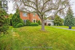 Toronto (Newtonbrook East) apartment for rent - A large tree stands in the middle of a well-manicured lawn in front of a red brick house.