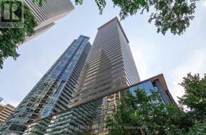 Toronto (Church-Yonge Corridor) condo for rent - A tall building with a glass facade stands in front of a tree.