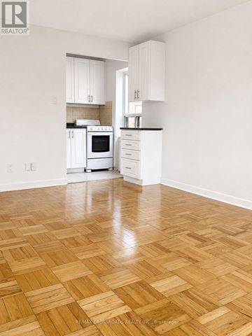 Toronto (Lawrence Park South) condo for rent - A kitchen with white cabinets and a wooden floor.