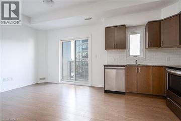 Kitchener condo for rent - A spacious kitchen with wooden cabinets and a stainless steel dishwasher.