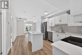 Hamilton (Ancaster) condo for rent - A modern kitchen with white cabinets and a black countertop.