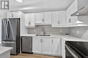 Hamilton (Ancaster) condo for rent - A kitchen with white cabinets and a stainless steel refrigerator.