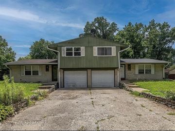 Indianapolis apartment for rent - A two-story house with a garage is surrounded by greenery.