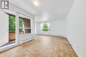 Hamilton (Durand) condo for rent - A room with a wooden floor and white walls, with a window showing greenery outside.