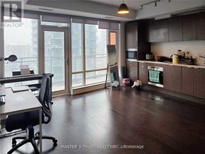Toronto (Waterfront Communities) condo for rent - A modern kitchen with dark wood floors and a desk with a chair.