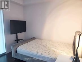 Toronto (Waterfront Communities) condo for rent - A bedroom with a bed, a television, and a lamp.