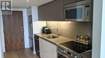 Toronto (Waterfront Communities) condo for rent - A kitchen with a sink, stove, and microwave.