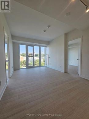 Toronto (Annex) condo for rent - A large, empty room with wooden floors and a view of the outdoors through the sliding glass doors.