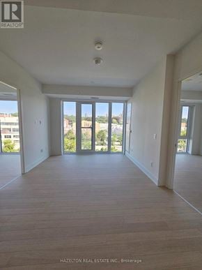 Toronto (Annex) condo for rent - A large, empty room with wooden floors and a view of the outdoors through large windows.