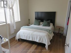 Fort Erie (Central) multi-family for rent - A bedroom with a bed, nightstand, and window.