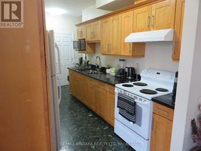 Fort Erie (Central) multi-family for rent - A kitchen with a white stove top oven and wooden cabinets.