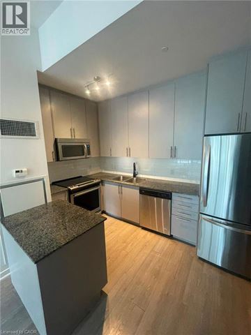 Kitchener condo for rent - A modern kitchen with stainless steel appliances and wooden floors.