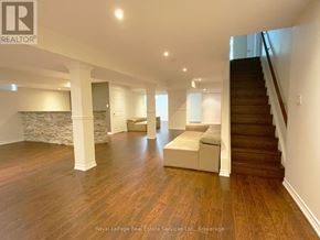 Oakville (Bc Bronte Creek) apartment for rent - A spacious room with wooden floors and a staircase.