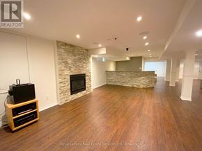 Oakville (Bc Bronte Creek) apartment for rent - A spacious living room with wooden flooring and a stone fireplace.