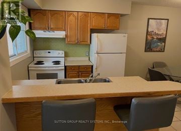 Kitchener townhouse for rent - A kitchen with wooden cabinets and a white fridge.