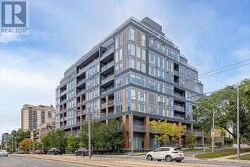 Toronto (Casa Loma) condo for rent - A modern multi-story building with a glass facade is the main focus of the image.