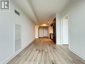 Toronto (Waterfront Communities) condo for rent - A long, empty hallway with wood flooring and white walls.