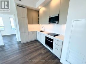 Vaughan (Vaughan Corporate Centre) condo for rent - A modern kitchen with white cabinets and a wooden floor.