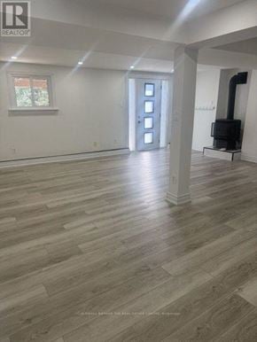 Barrie (Letitia Heights) apartment for rent - A large empty room with wood flooring and white walls.