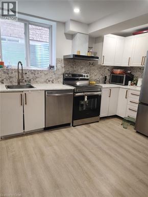 Kitchener apartment for rent - A kitchen with white cabinets and a stone backsplash.