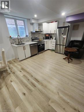 Kitchener apartment for rent - A kitchen with wooden floors and white cabinets.