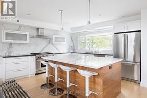 Toronto (Kensington-Chinatown) townhouse for rent - A modern kitchen with a white island and stools.