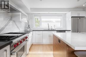 Toronto (Kensington-Chinatown) townhouse for rent - A modern kitchen with white cabinets and a black stove top.