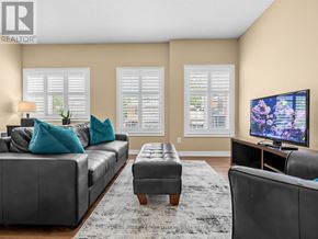 Vaughan (Kleinburg) apartment for rent - A living room with a grey couch, a black ottoman, and a television on a stand.