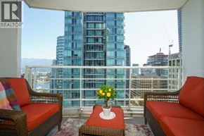 Vancouver apartment for rent - Two chairs and a table with a vase of flowers on a balcony overlooking a cityscape.