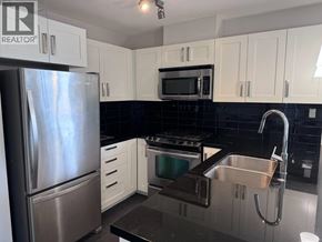 Burnaby apartment for rent - A kitchen with a stainless steel refrigerator, microwave, oven, and sink.