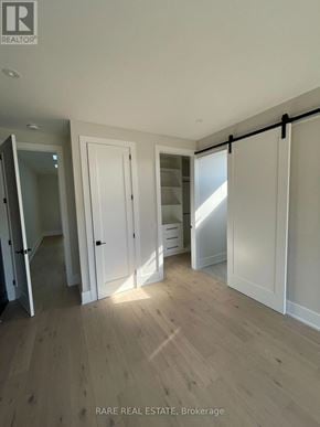 Toronto (Long Branch) apartment for rent - A room with wooden flooring and white walls, with a sliding door and a mirror.