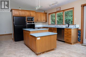 Arran-Elderslie apartment for rent - A kitchen with wooden cabinets and a black refrigerator.