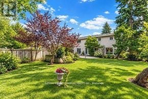 Mississauga (Sheridan) apartment for rent - A well-maintained lawn with a white house in the background and a tree with red leaves in the foreground.