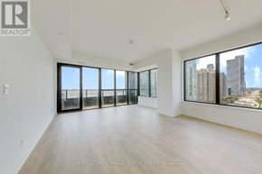 Mississauga (City Centre) condo for rent - A spacious room with wooden floors and large windows overlooking a cityscape.