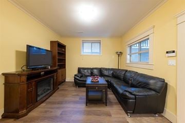 Surrey apartment for rent - A black leather couch sits in a living room with a wooden entertainment center.