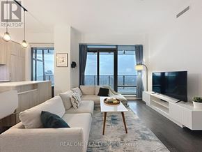 Toronto (Bay Street Corridor) condo for rent - A modern living room with a large window overlooking the city.