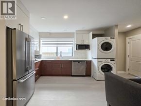 Burnaby apartment for rent - A modern kitchen with a refrigerator, microwave, and washing machine.