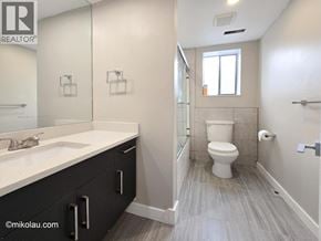 Burnaby apartment for rent - A bathroom with a toilet, sink, and mirror.